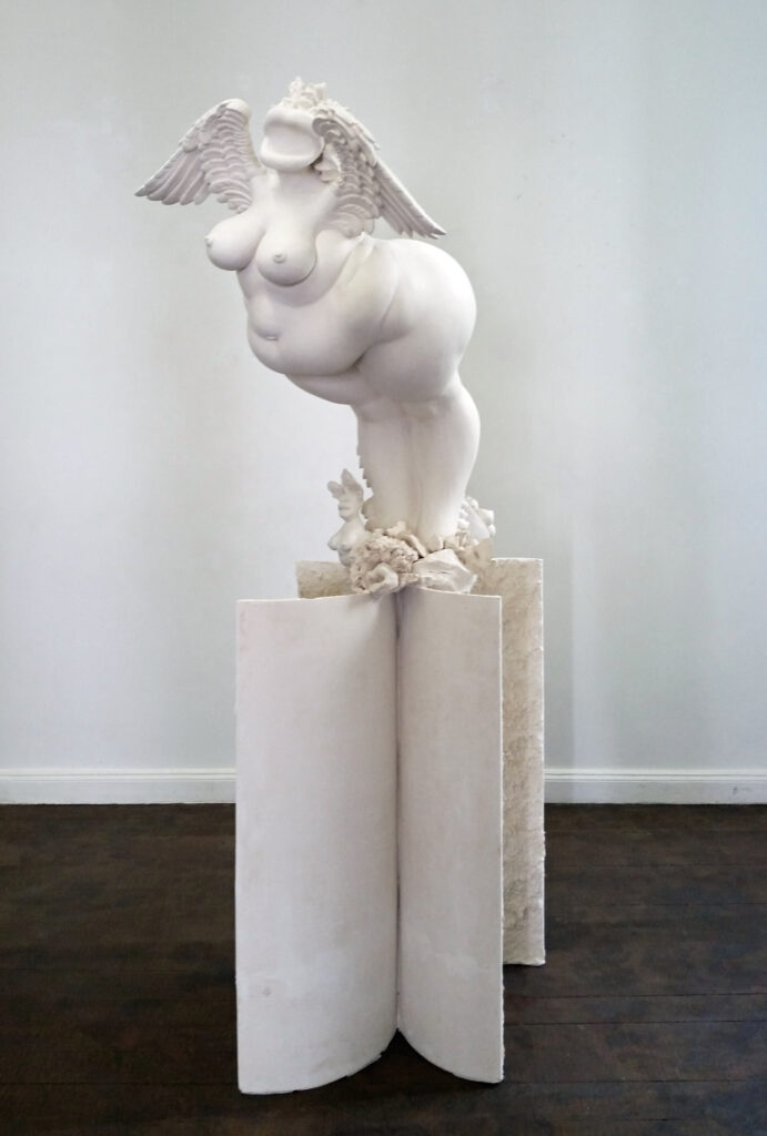 a voluptuous female figure with wings stands on two thin-walled cylinder halves.she is surrounded by smaller female figures and mixed creatures and ornaments.the sculpture is made of acrystal and is approx. 220cm high.