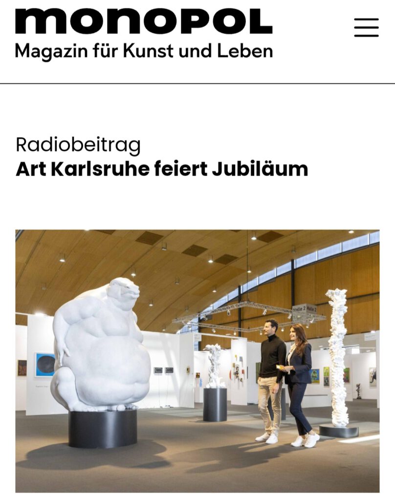 article at monopol about art karlsruhe with dee sculpture newt, a 2meter high white newt, visitors and ornamental columns in the background